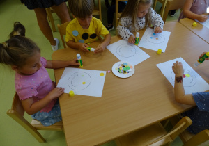 Dzieci tworzą pracę z kolorowych kółeczek