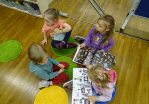 Dzieci siedzą na podłodze i oglądają książi.