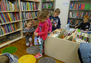 Dzieci oglądają książki na półkach.