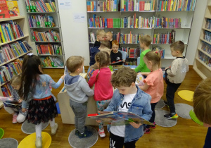 Dzieci oglądają książki na półkach.