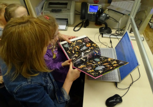 Dziewczynka wprowadza książkę do komputerowego systemu bibliotecznego.