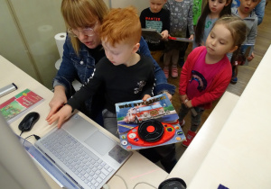 Chłopiec wprowadza książkę do komputerowego systemu bibliotecznego.