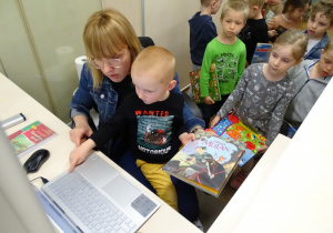 Chłopiec wprowadza książkę do komputerowego systemu bibliotecznego.
