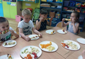 Dzieci jedzą szaszłyki z owoców