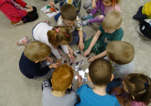 Dzieci układają puzzle na dywanie.