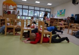 Dzieci bawią się przechodząc pod krzesełkami.
