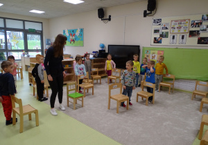 Dzieci bawią się stojąc obok krzesełek.