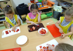Dzieci kroją owoce na tackach.