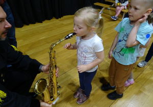 Dziewczynka dmucha w saksofon.