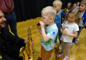 Chłopiec dmucha w saksofon.