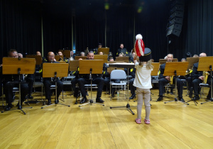 Dziewczynka dyryguje orkiestrą.