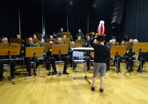 Chłopiec dyryguje orkiestrą.