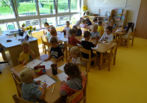 Dzieci rysują przy stolikach.