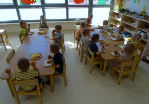 22 Dzieci siedzą przy stolikach i jedzą