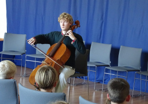 Dzieci słuchają jak pan gra na wiolonczeli