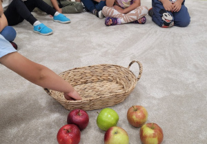 Dzieci siedzą w kole i liczą jabłka