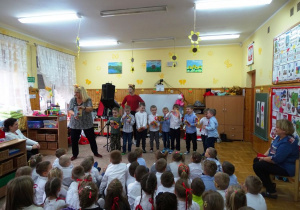 Dzieci stojace na scenie mają w rękach książeczki i z nimi tańczą