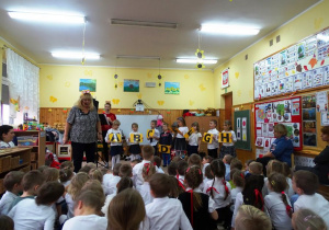 Dzieci stoją na scenie, w rękach mają kartoniki z literami alfabetu