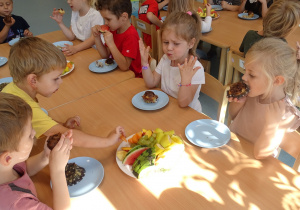 Dzieci jedzą babeczki i owoce