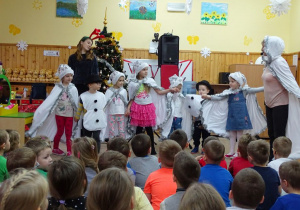 Dzieci przebrane za śnieżynki i bałwanki stoją na scenie