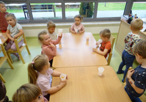 Dzieci przy stolikach piją sok