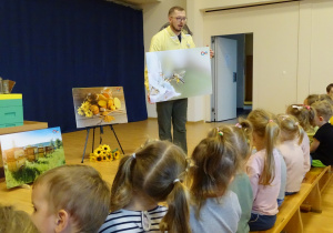 Pszczelarz pokazuje dzieciom ilustrację pszczoły