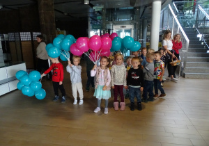 Dzieci pozują do zdjęcia z różowymi i niebieskimi balonami.
