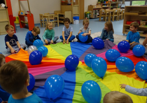 dzieci siedzą z balonami na chuście