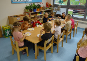 dzieci siedza przy stolikach