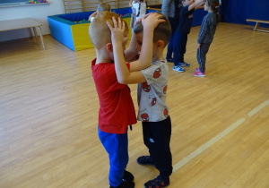 Dzieci tańczą w parze trzymając swoje głowy.