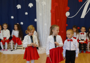 Dzieci recytują wiersz przez mikrofon.