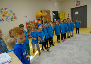 Dzieci stoją ubrane na niebiesko.