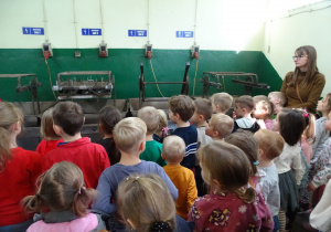 Dzieci oglądają maszyny do malowania srebrem wnętrza bombek.
