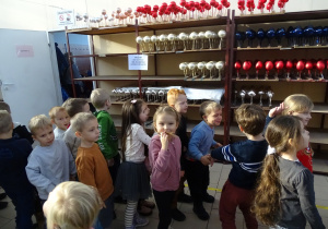 Dzieci stoją przy regale z bombkami.