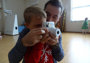 Chłopiec z panem robią zdjęcie aparatem.
