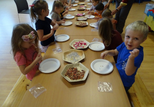 Dzieci podczas warsztatów tworzenia bransoletek z koralików