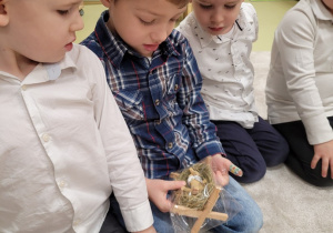 Dzieci oglądają figurki stajenki i żłóbka z Jezuskiem