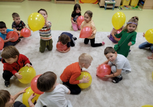 Dzieci kucają z balonami