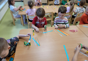 Dzieci wykonują łańcuch na choinkę z papieru