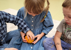 Dzieci dekorują pomarańczę goździkami