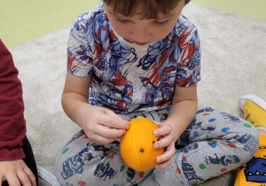 Dzieci dekorują pomarańczę goździkami