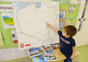 Chłopiec wskazuje stolice na mapie