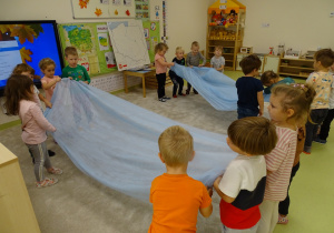 Dzieci wachlują niebieskim materiałem imitującym Wisłę