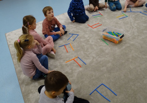 dzieci układają literę F z patyków