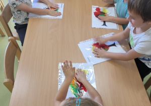 Dzieci rozcierają farbę wlaną do koszulek foliowych