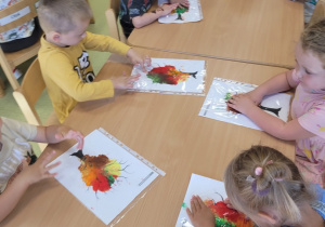 Dzieci rozcierają farbę wlaną do koszulek foliowych