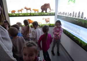 Dzieci oglądają obrazki ze zwierzętami prehistorycznymi.