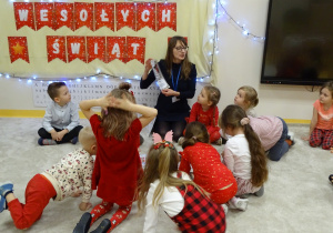 Pani pokazuje dzieciom obrazki i opowiada o tradycjach bożonarodzeniowych.