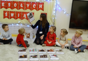 Pani pokazuje dzieciom obrazki i opowiada o tradycjach bożonarodzeniowych.