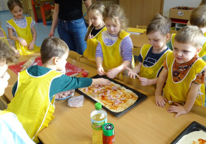 Dzieci kładą szynkę na pizzę